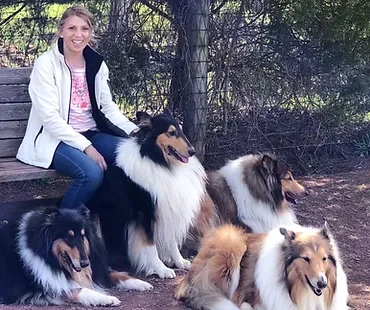 Photo of FLora Scheck on a bench with 4 Rough Collies sitting at her feet