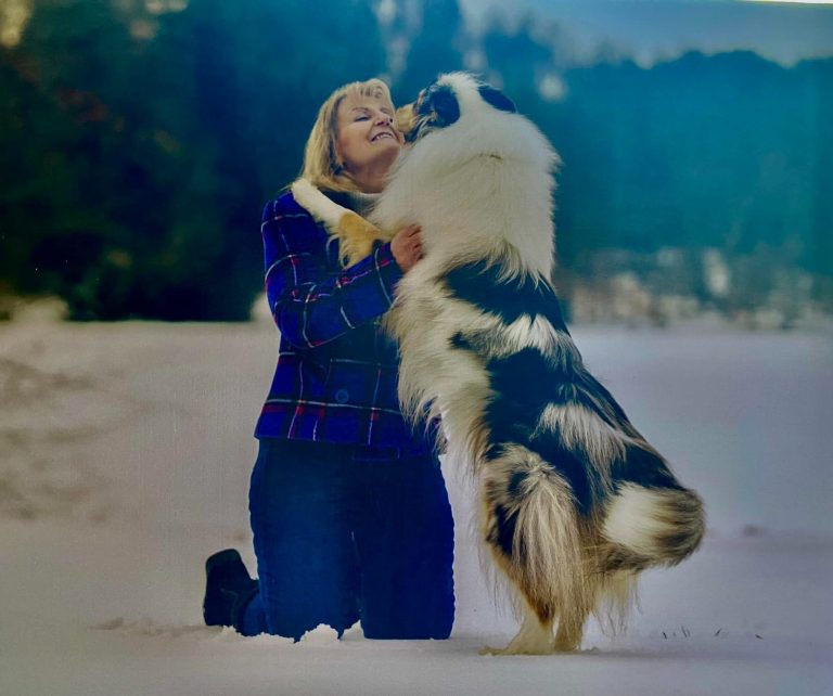 Photo of Kerry Boyce on her knees with a Rough Collie hugging her